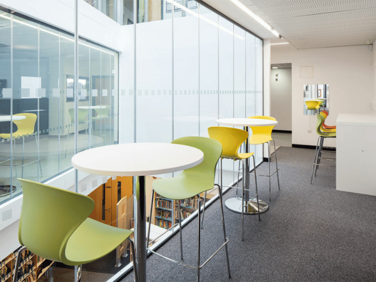 Lounge area with round bar height tables and colorful chairs.