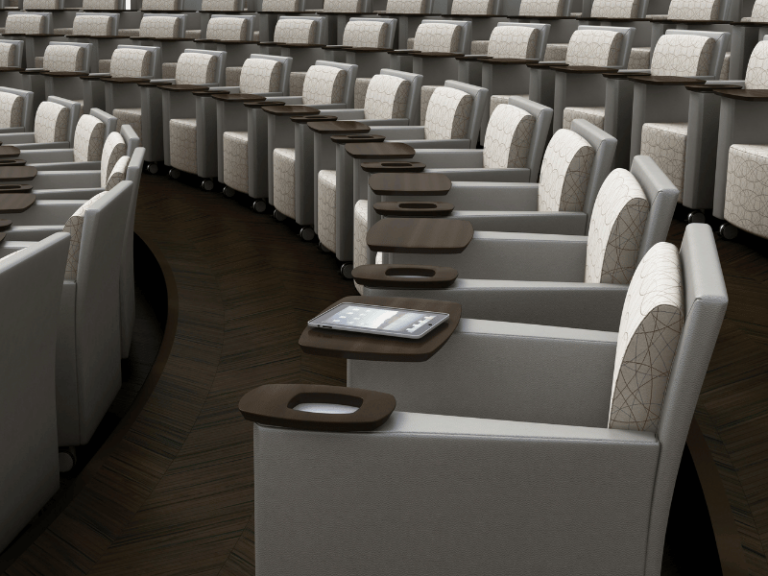 Lecture hall featuring upholstered chairs that include a tablet arm and cupholder,