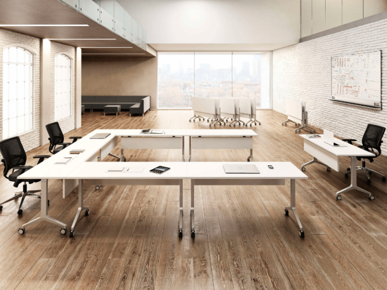 A classroom environment featuring white flip-top tables on casters in a u-shape configuration.