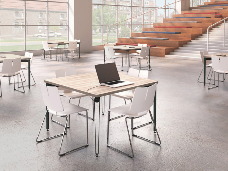 Tiered lecture hall that has bench seating with square tables and and stackable chairs on the main level.