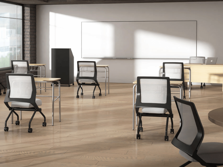 An open classroom with a lectern in the front and multiple desks with chairs on casters.